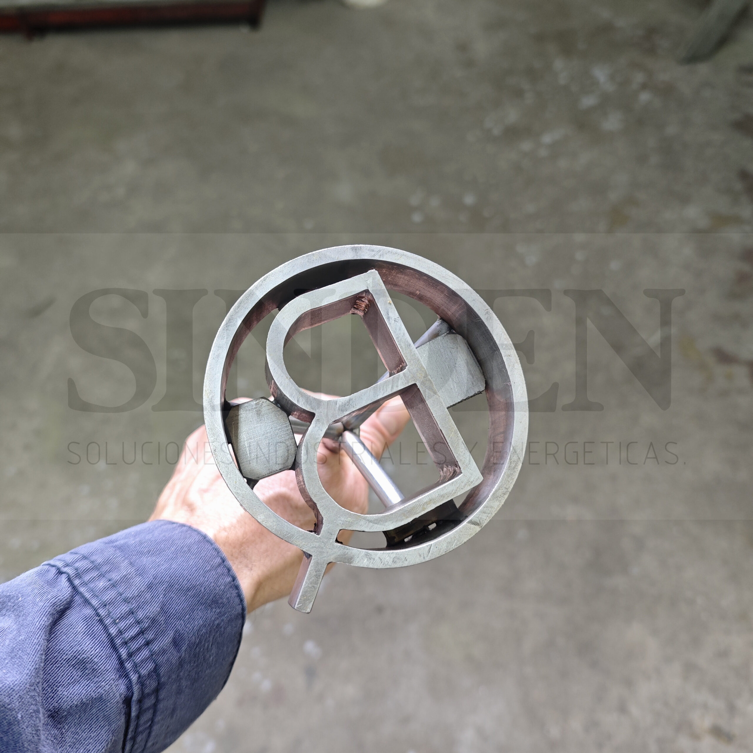 Marca redonda con letras en acero inoxidable, sostenida en el taller