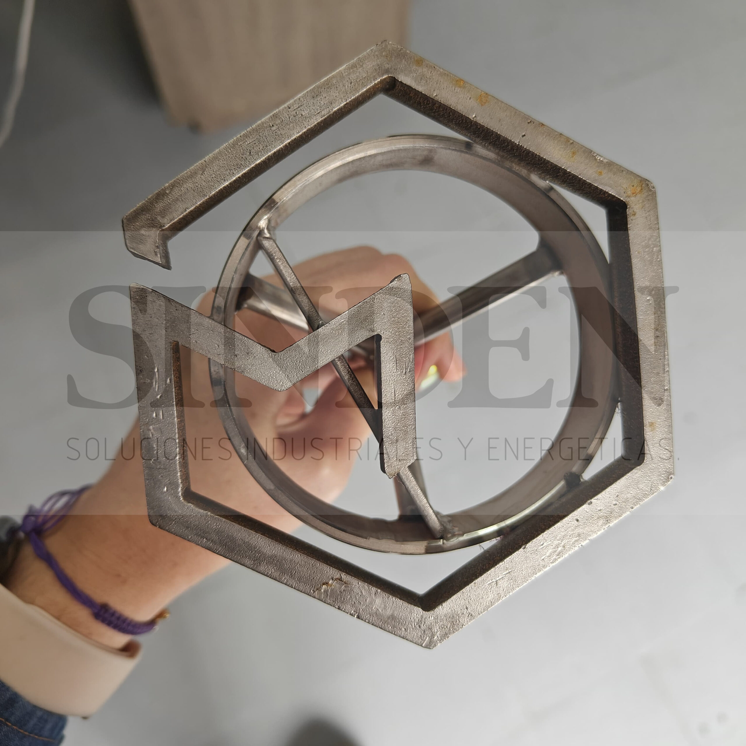 Marca hexagonal con letras, sostenida en la mano