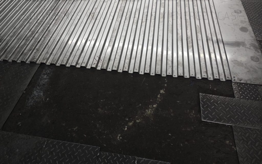 Láminas dobladas en canales para un piso de furgón, extendidas en el taller de SINDEN