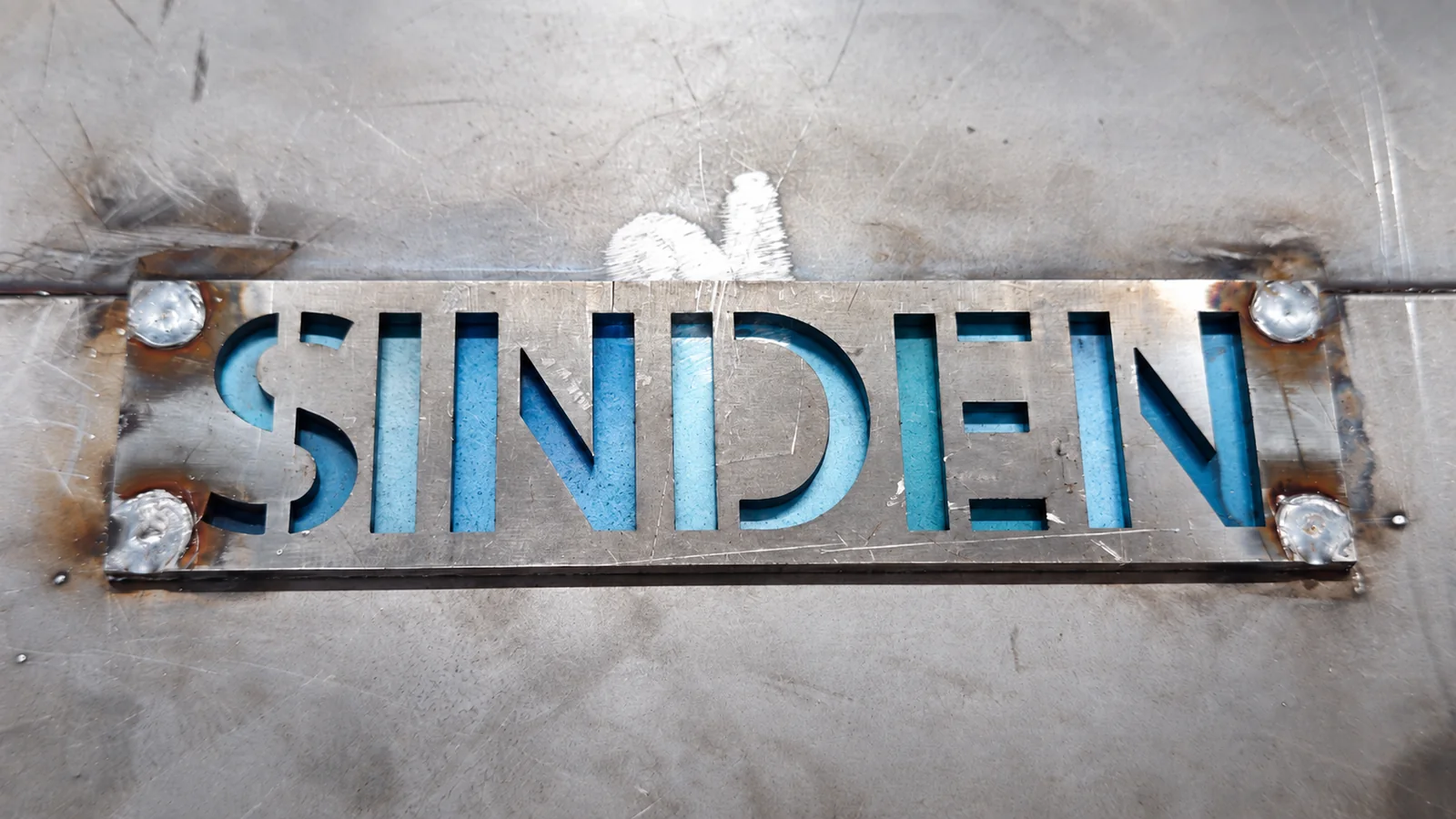 Placa con el nombre SINDEN cortado en lámina de hierro, con las letras en azul